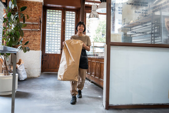 Bakery worker carrying flour sack in artisan bakery