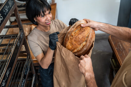 Artisan baker hands over fresh sourdough loaf in bakery
