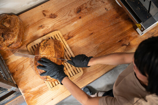 Artisan baker slicing rustic sourdough on wooden counter