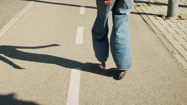Gimbal follow shot tracking woman on inline skates from behind on sunny urban promenade. Wide jeans, red wheels, three dramatic long shadows on concrete. Speed, motion blur, dynamic urban active lifes