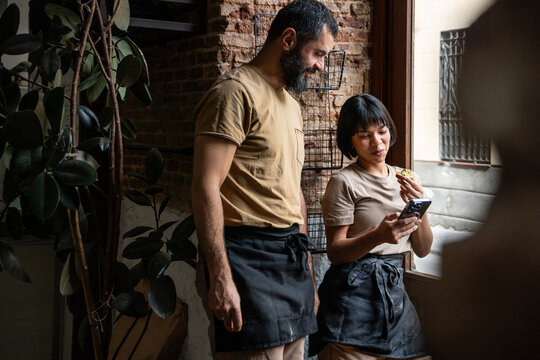 Artisan bakery staff checking phone order in rustic shop