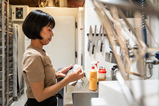 Baker cleaning pastry equipment in an artisan bakery kitchen