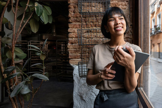 Baker taking inventory in artisan bakery by window
