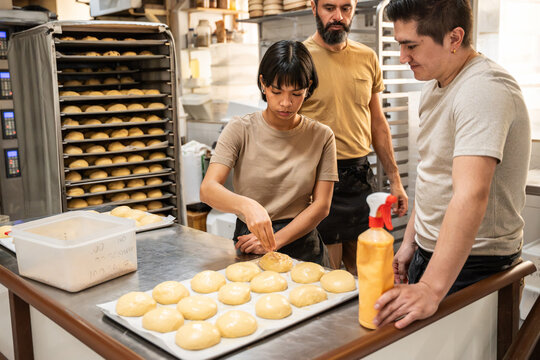 Artisan bakers shaping dough balls in a busy bakery kitchen