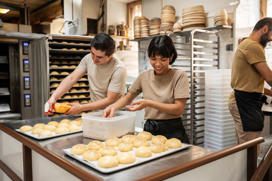 Artisan bakery team preparing dough and rolls in kitchen
