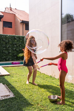 Mother and daughter making giant bubbles in sunny backyard