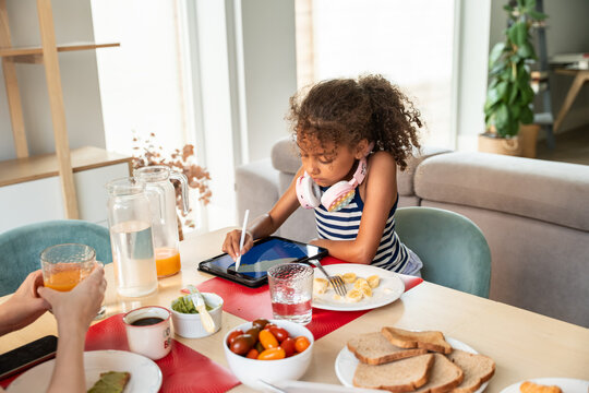 Girl using tablet at breakfast table in modern home