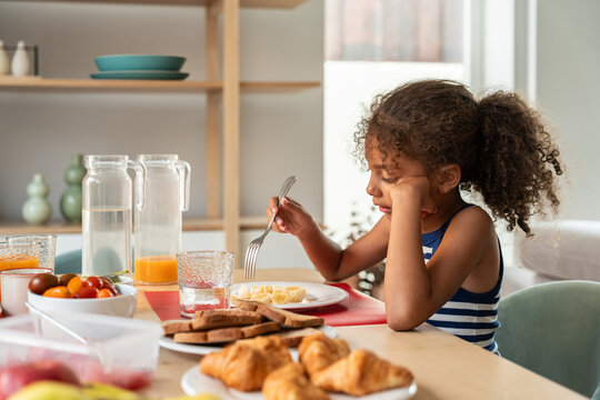 Young girl looking bored at breakfast table in kitchen