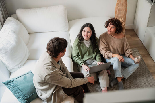 Friends talk at home while planning with a laptop together