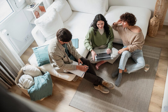 Young adult planning project on sofa with laptop at home