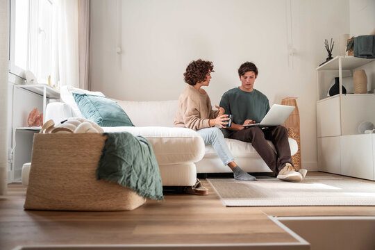Couple planning finances on laptop in bright living room