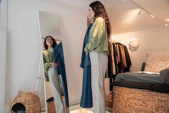 Woman choosing outfit in bedroom wardrobe by mirror