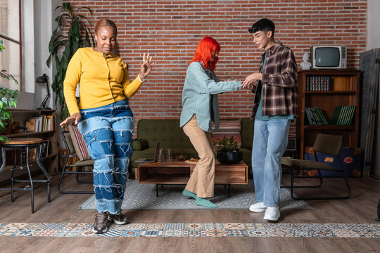 Friends dancing together in a cozy living room at home