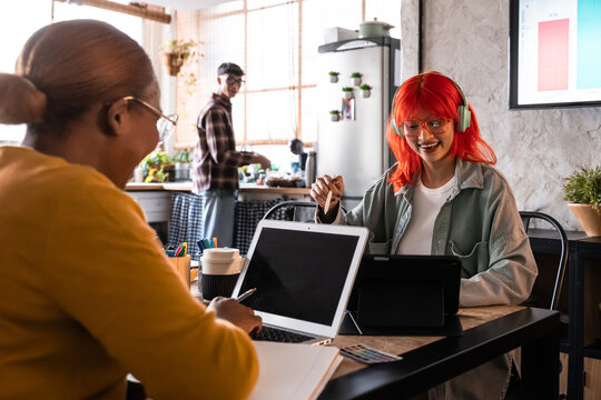 Two friends working on laptops in cozy home kitchen