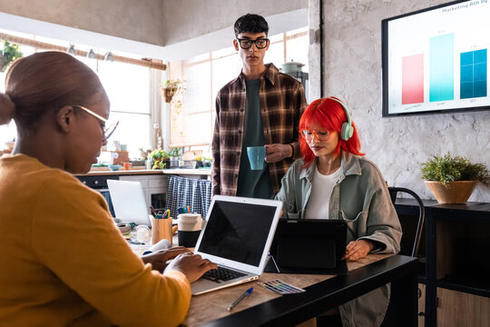 Diverse team working on laptop in modern office meeting