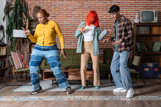 Friends dancing in a cozy living room with brick wall