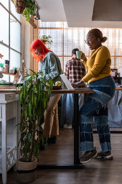 Coworkers in cozy kitchen  using laptop and sipping coffee