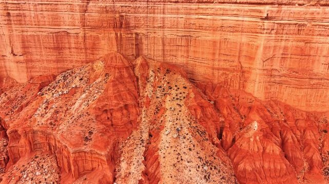 Drone view of layered red clay cliffs in Spain. Oblique drone view of red and tan eroded clay cliffs with horizontal strata and gullies.