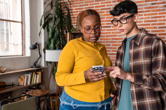 Coworkers reviewing smartphone message in modern office space