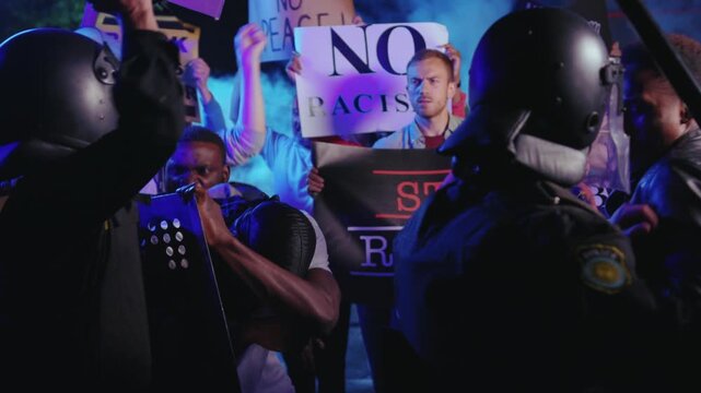 Black lives matter. Crowd of aggressive strong multi-racial people fighting and arguing with police officers on night street riot. Antiracism rally. Demonstration.