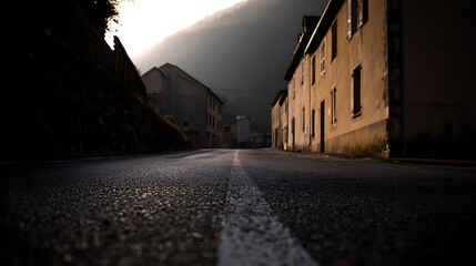Naklejka premium Low angle view of a misty, atmospheric narrow road with old town buildings at dusk or dawn, with soft, natural light and a mysterious mood