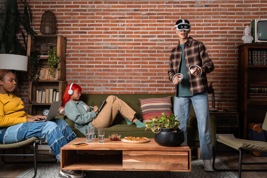 Friends relaxing at home with virtual reality and laptop