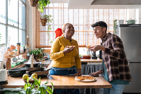 Friends sharing pizza and laughter in a sunny kitchen