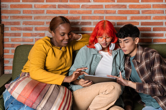 Friends on sofa browsing tablet and sharing ideas together