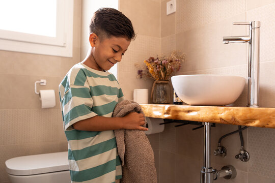 Hispanic boy drying hands in bathroom during family routine