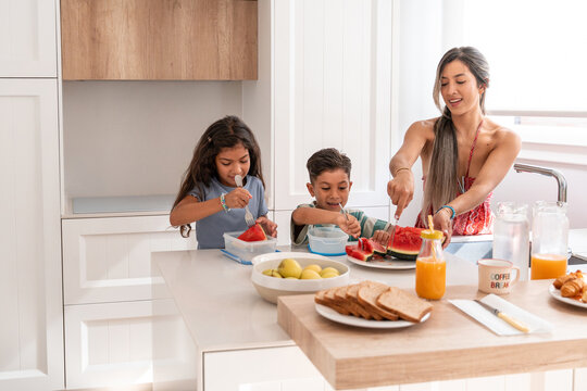 Hispanic family enjoying fresh breakfast at home kitchen
