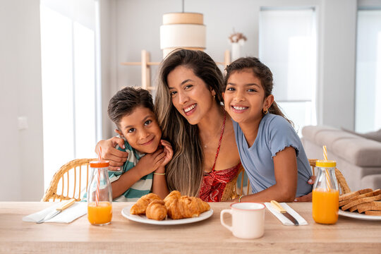 Hispanic mother and children looking at camera during breakfast time