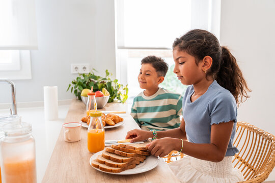 Hispanic siblings serving breakfast at home kitchen