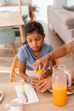 Hispanic mother helping daughter with juice at home