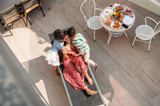 Hispanic family relaxing together on sunny hotel terrace