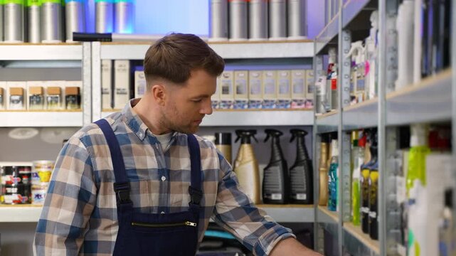Auto detailer selecting car care product from shelf