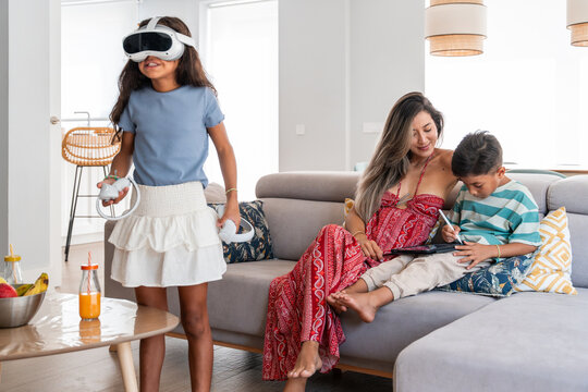 Hispanic family relaxing at home with VR and tablet play