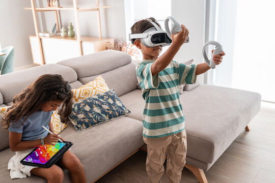 Hispanic family kids enjoying VR and tablet at home