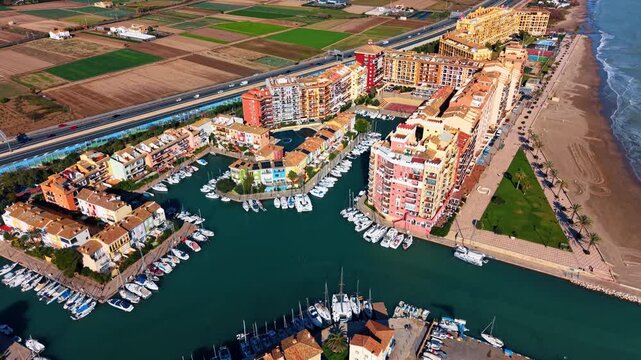 Aerial view of Port Saplaya marina and beach. Top-down aerial view of Port Saplaya marina, beach, apartments, boats and fields in Valencia, Spain.