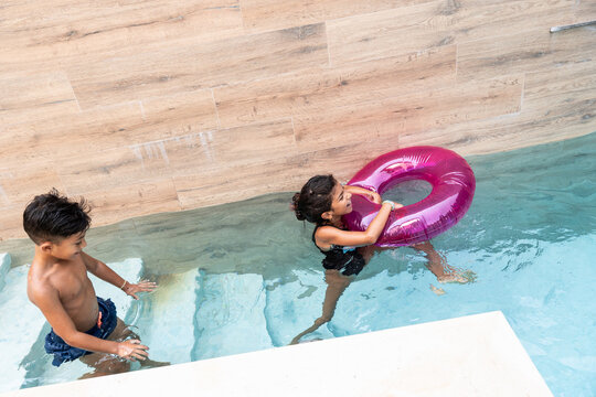 Hispanic family children playing with swim ring in pool