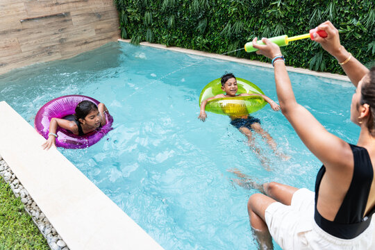 Hispanic family enjoying pool play with float rings