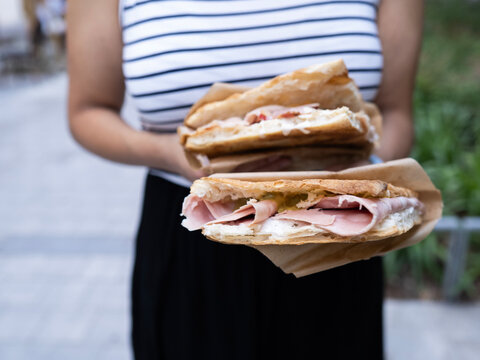 Person holding focaccia sandwich wrapped for takeaway lunch