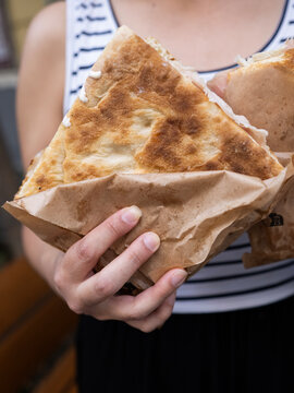 Woman holding focaccia slice in paper bag, close up