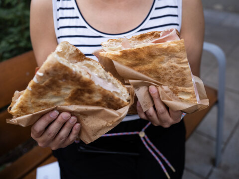 Person holding focaccia sandwiches wrapped in paper
