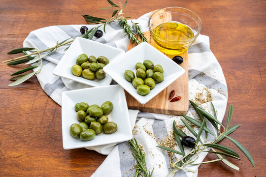 Green olives with olive oil, herbs and rustic table setting