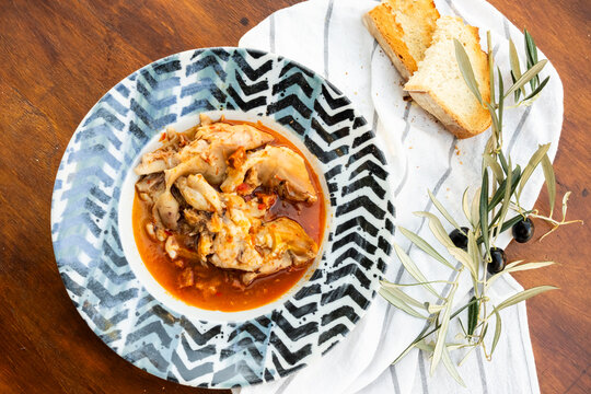 Rustic plate of stewed pig's feet with bread and olives