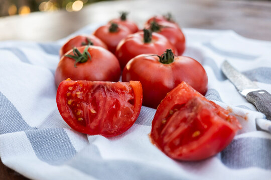 Fresh ripe tomato on kitchen towel with cut wedges and knife