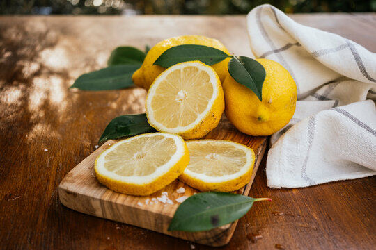 Fresh lemon slices and whole citrus on rustic board