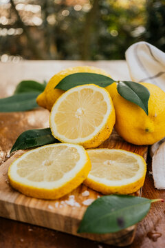 Fresh lemon slices with leaves on rustic cutting board
