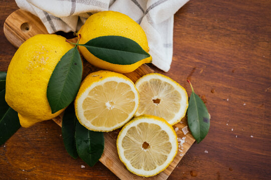 Fresh lemon slices with leaves on rustic wooden board