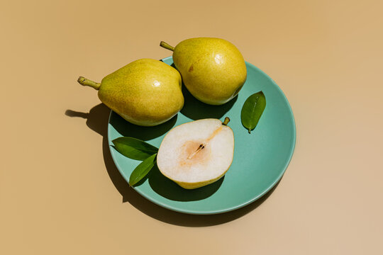Fresh pears on turquoise plate with leaves on beige